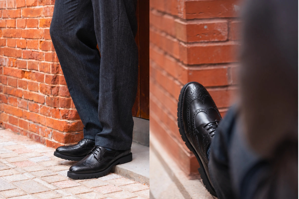 Black wingtip Derby shoes with chunky lug soles, shown worn with charcoal trousers and in a close-up beside a brick wall.