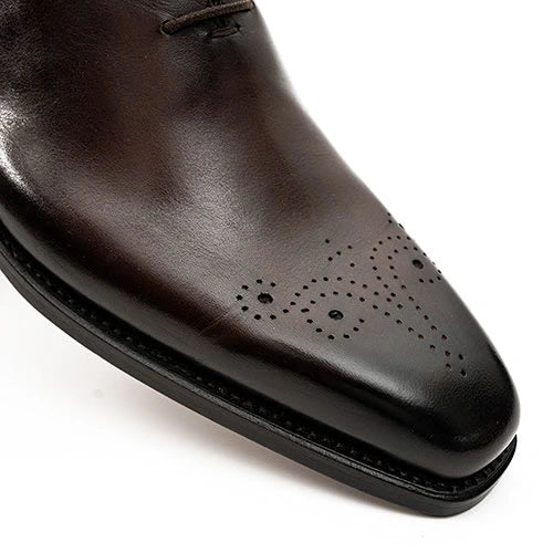 Close-up of a dark brown leather dress shoe with a perforated toe medallion