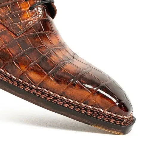 Close-up of a glossy brown crocodile-pattern shoe with prominent braided stitching along the sole edge